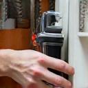 A professional installing a finished kitchen cabinet.
